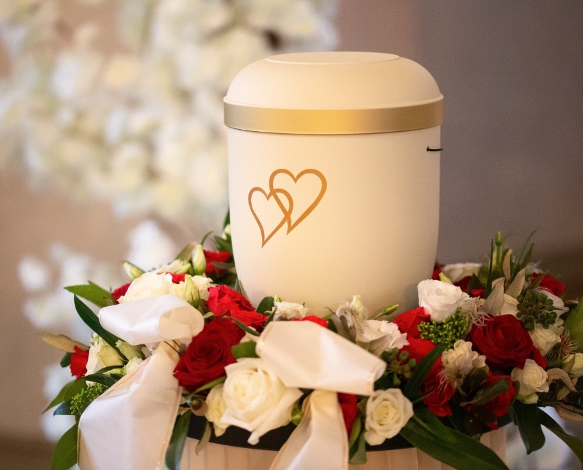 iebevoll geschmückte Urne mit roten und weißen Blumen bei einer würdevollen Feuerbestattung